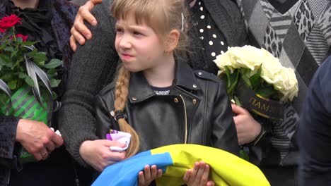 Una-Hermosa-Niña-Ucraniana-Sostiene-Una-Bandera-En-El-Funeral-De-Su-Padre-En-Liviv,-Durante-La-Guerra-De-Ucrania