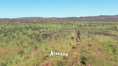 Excelente-Toma-Aérea-Del-Cartel-Del-Alerón-En-Australia-Con-Una-Estatua-Gigante-De-Un-Hombre-Aborigen-Detrás