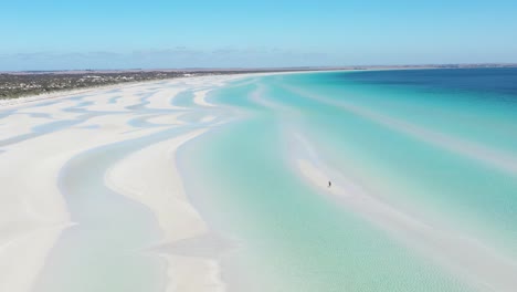 Excelente-Toma-Aérea-De-Una-Persona-Parada-En-Las-Arenas-Blancas-De-La-Playa-Flaherty,-Cerca-Del-Agua-Azul-Clara,-En-La-Península-De-Yorke,-Australia