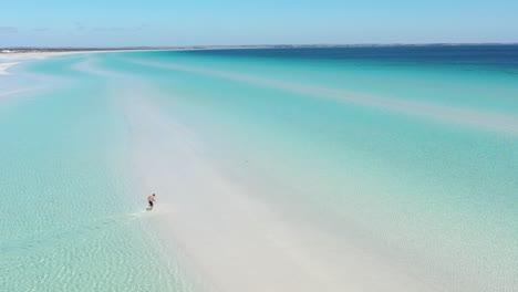 Excelente-Toma-Aérea-De-Un-Hombre-Corriendo-Por-Las-Playas-De-Arena-Blanca-Y-El-Agua-Azul-Clara-De-La-Playa-Flaherty-En-La-Península-De-Yorke,-Australia