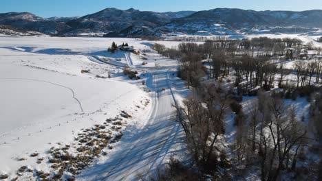 Excelente-Vista-Aérea-De-Un-Coche-Conduciendo-Por-Una-Carretera-Nevada-Hacia-Steamboat-Springs,-Colorado