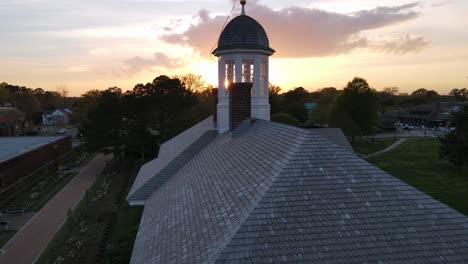 Excelente-Vista-Aérea-De-Un-Edificio-Histórico-Coronado-Con-Una-Veleta-Al-Atardecer-En-Williamsburg,-Virginia