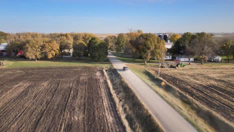 Dron-Aéreo-Después-De-La-Toma-De-Una-Camioneta-Que-Conducía-Por-Un-Polvoriento-Camino-De-Grava-Bajo-Un-Cielo-Azul-En-Las-Zonas-Rurales-Del-Medio-Oeste-De-Iowa