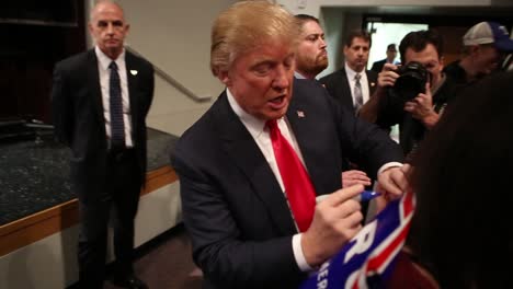 El-Candidato-Presidencial-Donald-Trump-Firma-Un-Autógrafo-Para-Una-Partidaria-Y-Votante-Durante-Un-Mitin-De-La-Campaña-Primaria-Del-Caucus-Republicano-De-Iowa