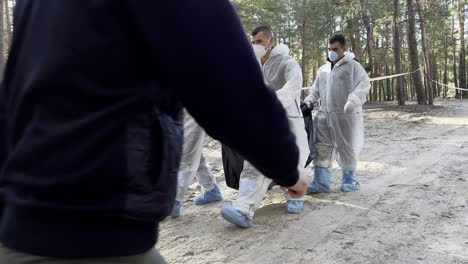 Investigadores-De-Crímenes-De-Guerra-Trasladan-Cadáveres-En-Bolsas-Para-Cadáveres-Desde-Fosas-Comunes-En-Izium,-Ucrania,-Tras-La-Liberación-De-La-Región-De-La-Ocupación-Rusa