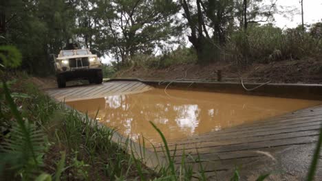 Slow-Motion-Of-A-Us-Marine-Joint-Light-Tactical-Vehicle-Plowing-Through-A-Muddy-Water-Hazard-On-Okinawa,-Japan