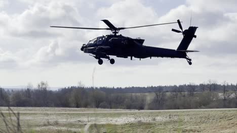 Medium-Shot,-Ah-64-Apache-Helicopter-Hovers-In-Place-Over-Grassy-Field-At-The-Grafenwoehr-Training-Area,-Germany