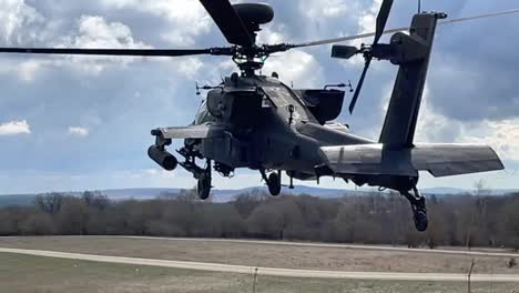 Slow-Motion,-Ah-64-Apache-Helicopter-Hovers-In-Place-Over-Grassy-Field-At-The-Grafenwoehr-Training-Area,-Germany