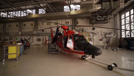 Aerials-Of-Us-Coast-Guard-Mh-65-Helicopter-In-Flight-And-Ground-Crew-Working-In-A-Maintenance-Hanger,-Florida