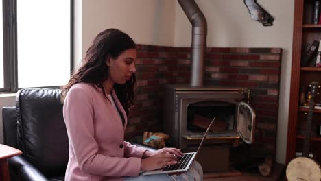 A-Young-Woman-Types-On-Her-Laptop-In-Front-Of-An-Old-Fashioned-Furnace