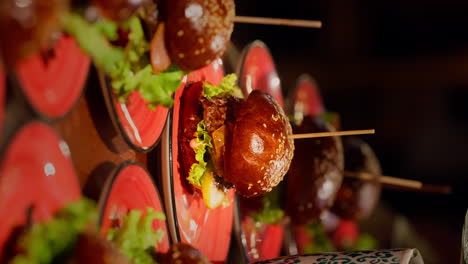 Vertical-Video-of-Delicious-Fresh-Tasty-Hamburgers-on-Colorful-Plates,-Studio-Shot-with-Mirror-Reflection-in-Background