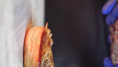 Chef-assembling-the-hamburger-meat-on-top-of-the-bun,-sauce-and-onion