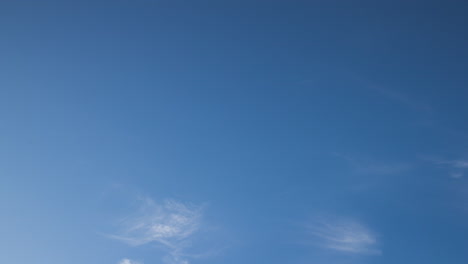 Time-lapse-of-fast-moving-clouds-during-a-sunny-day-in-the-blue-sky-with-the-transition-to-evening-hours-along-with-the-occasional-flight-of-the-aircraft-leaving-white-traces-on-a-flyby