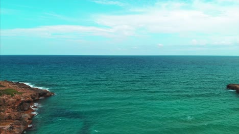 AERIAL-DOLLY-IN:-Drone-flying-over-Calamosche-beach,-in-the-Vendicari-Reserve,-a-seaside-paradise-of-Sicily,-Italy,-with-an-incredible-beach-and-rock-formations