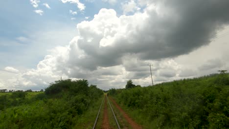 Eine-Zeitlupenperspektive,-Die-Von-Einem-Zug-Aus-Aufgenommen-Wurde,-Der-Sich-Langsam-Entlang-Einer-Eisenbahnstrecke-Im-Ländlichen-Afrika-Bewegt-Und-Zu-Den-Wolken-Aufschaut