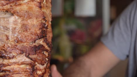 Popular-and-traditional-Greek-gyros,-grilled-and-cut-on-vertical-rotisserie-spinning-by-a-man-in-slow-motion