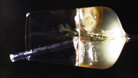 Vertical-closeup-of-a-white-light-cocktail-get-mixed-with-a-lemon,-rosemary-herb-and-icecubes-inside