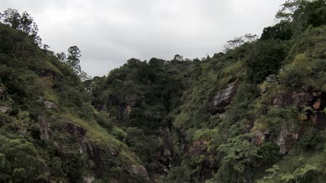 Muñeca-Aérea-Volando-Sobre-Las-Cataratas-De-Ravana-Escondidas-En-Un-Acantilado-Cubierto-De-Una-Densa-Selva-Verde-En-Un-Día-Nublado,-Sri-Lanka