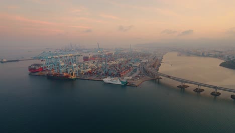 Luftaufnahme-In-Richtung-Hafen-Von-Algeciras-Gestapelte-Container-Und-Verladekräne-Terminal-Bei-Sonnenaufgang