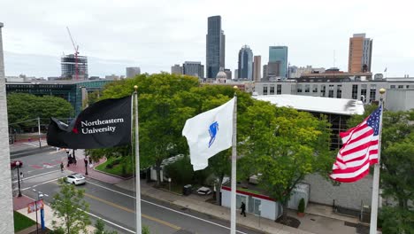 Toma-Aérea-De-Banderas-Ondeando-En-El-Viento-Con-El-Fondo-Del-Horizonte-De-Boston