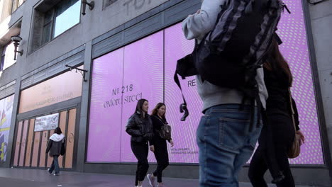 In-slow-motion-people-walk-past-an-empty-shop-space,-known-as-“dead-spaces”,-on-Argyll-Street-near-Oxford-Circus