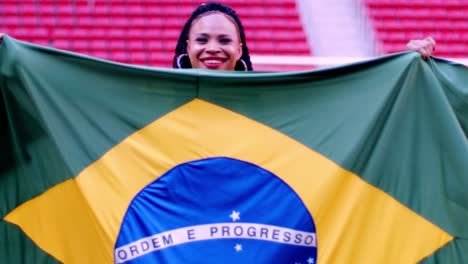 Female-soccer-fan-holding-Brazilian-flag-on-a-field-in-Mane-Garrincha-stadium