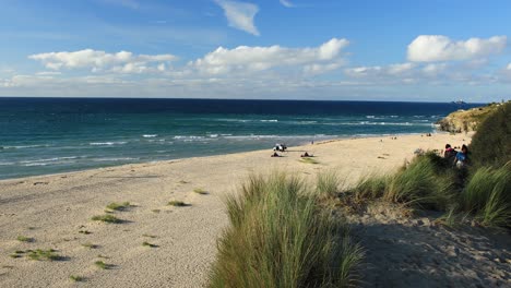 Couple-Walking-Towards-Hayle-Sandy-Beach-To-Watch-Seascape,-Cornwall,-England