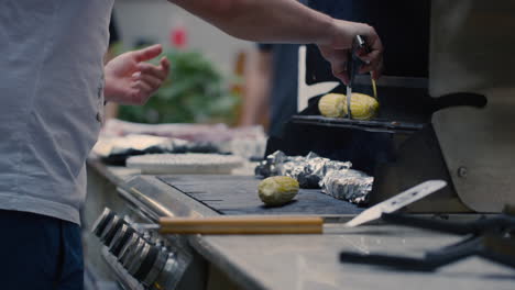 Low-Angle-View-Of-Male-Placing-Fresh-Corn-Cob-On-Top-Rack-On-BBQ-Grill