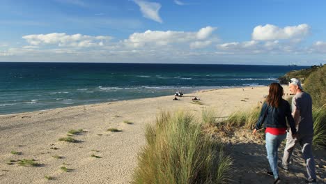 Couple-Walking-Happily-Towards-Hayle-Sandy-Beach-To-Watch-Surfers,-Cornwall,-England