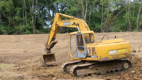 Excavadora-Hidráulica-Deere-Apisonando-La-Suciedad-En-El-Fondo-Del-Estanque-En-Un-Sitio-De-Desarrollo-De-Tierras