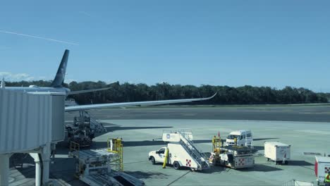 Toma-Panorámica-De-Un-Avión-Aterrizando-En-El-Aeropuerto-De-Cancún-Con-Otro-Avión-En-Tránsito-Y-Dos-Aviones-Estacionados