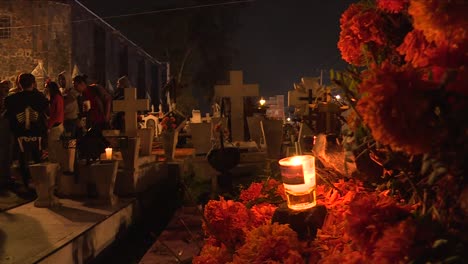 Brennende-Kerze-über-Cempasuchitl-Blumen-Vor-Einem-Grab-Auf-Einem-Traditionellen-Friedhof-In-Mixquic,-Mexiko