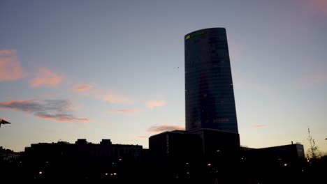 Iberdrola-Tower-Electricity-Consortium-Silhouette-In-Der-Abenddämmerung-Mit-Vorbeifliegendem-Flugzeug,-Breite-Einspielung