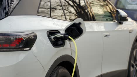 Electric-car-charging-on-parking-lot-with-car-charging-station-on-city-street