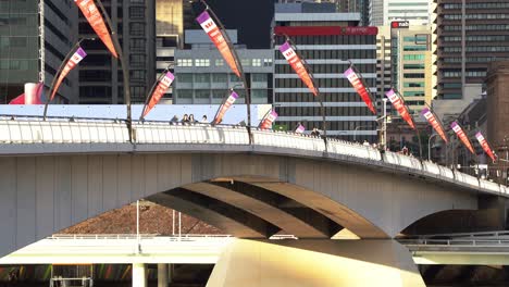 Fußgänger-Schlendern-über-Die-Victoria-Bridge-In-Richtung-Südufer-Bei-Sonnenuntergang-Goldenen-Stunden-Mit-Bussen,-Die-Die-Brücke-überqueren,-Und-Westpac-werbebannern,-Die-Entlang-Der-Brücke-Wehen-Und-Statische-Aufnahmen-Erzeugen