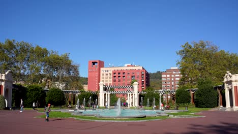 Fuente-En-El-Parque-Doña-Casilda-Con-Fuente-De-Chorro-De-Agua-Y-Gente-Caminando-En-El-Fondo,-Gran-Angular