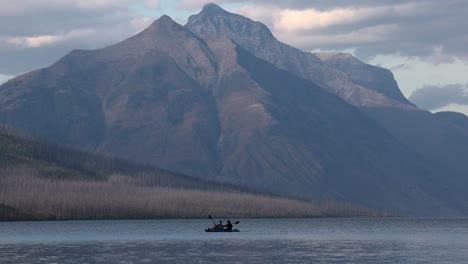 Paar-Sitzt-Auf-Paddelbrettern-Und-Paddelt-Mit-Den-Wunderschönen-Bergen-Des-Glacier-National-Park-Im-Hintergrund