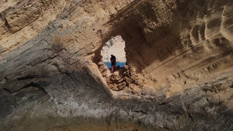 Couple-standing-in-a-cave-on-a-cliff,-kissing-each-other-in-Sa-Pedrera-de-Cala-D'Hort,-Spain