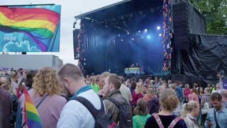 Crowd-of-people-and-glowing-stage-of-Oslo-Pride-2022,-pan-right-view