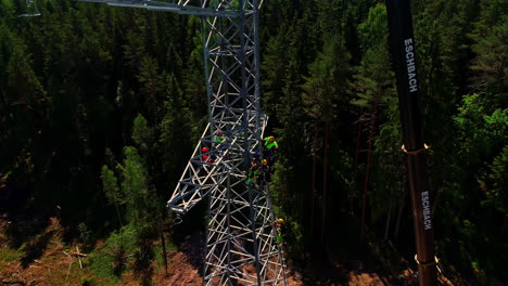 Una-Tripulación-Sube-A-La-Torre-De-Transmisión-Eléctrica-Para-Instalar-Los-Cables---Vista-Aérea-Inclinada-Hacia-Abajo