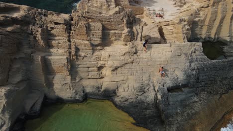 2-guys-climbing-down-a-dangerous-cliff-in-Sa-Pedrera-de-Cala-D'Hort,-Spain