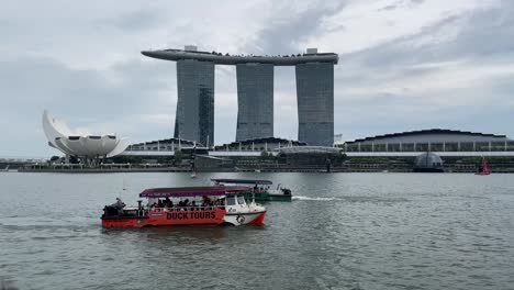 Barcos-De-Turistas-Que-Navegan-A-Lo-Largo-Del-Río-Singapur-Frente-A-La-Vista-Del-Icónico-Museo-De-Arenas-Y-Arte-De-La-Bahía-De-Marina-En-Singapur