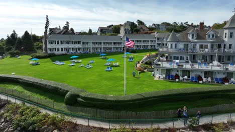 Tourists-enjoy-views-from-walking-trail-by-Victorian-bed-and-breakfast-manor-in-New-England-USA-flag-waving-in-breeze