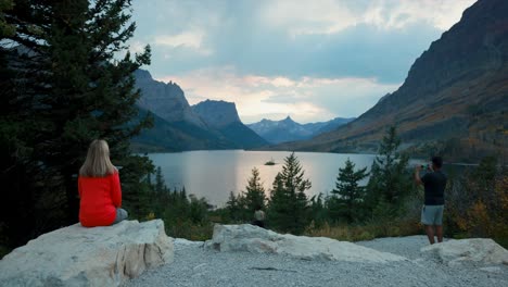 Woman-sitting-on-a-rock-enjoying-the-view-as-other-people-stop-by-and-capture-fotos-and-memories