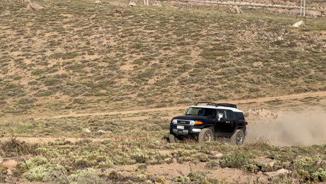 Blick-Auf-Einen-4x4-Geländewagen,-Der-Auf-Einer-Unbefestigten-Straße-Fährt-Und-In-Der-Wüstenberglandschaft-Zum-Parken-Hochfährt