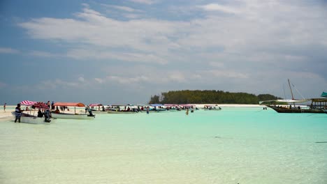 Snorkeling-tour-boats-arriving-on-shore-with-tourists-for-diverse-activities,-Locked-wide-shot