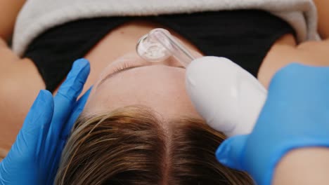 A-facial-being-done-on-a-young-caucasian-woman-by-an-aesthetician-with-blue-medical-gloves-on