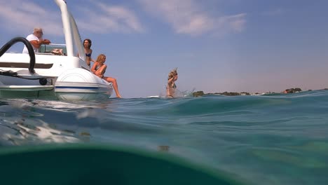 Split-underwater-scene-of-woman-diving-in-calm-sea-from-nautical-vessel