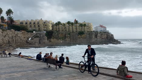 Azarujinha-Strand-Mit-Sehr-Rauer-See,-Mehrere-Menschen-Beobachten-Die-Wellen-Des-Meeres,-Im-Hintergrund-Eine-Hohe-Klippe-Mit-Einigen-Schönen-Wohngebäuden