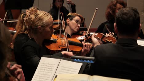 Medium-handheld-shot-of-talented-violin-player-in-an-orchestra-during-a-concert-to-classical-music-by-mozart-with-wooden-violins-in-slow-motion